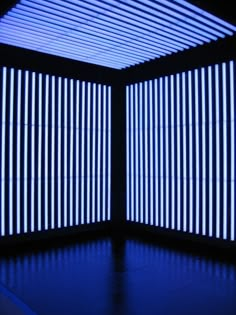 an empty room with blue lighting in the ceiling and vertical lines on the wall behind it