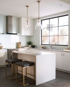 a kitchen with an island and two stools in front of the counter top area