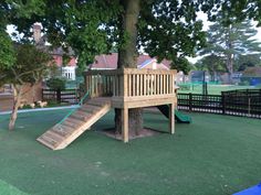 a playground with a tree, slide and play ground