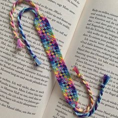 an open book with a colorful string on top of it next to a pair of scissors