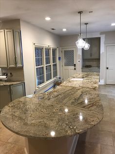 a large kitchen with an island in the middle and marble counter tops on both sides