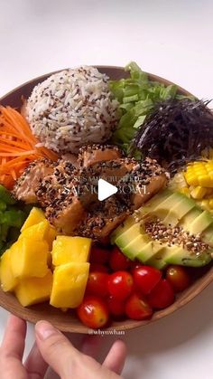 a person holding a wooden bowl filled with different types of food