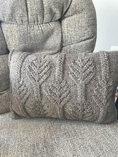 a pair of pillows sitting on top of a couch next to a pillow that has been knitted