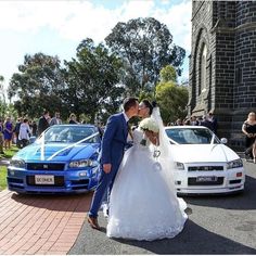 a bride and groom kissing in front of their wedding cars