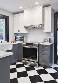 a kitchen with black and white checkered flooring, stainless steel appliances and cabinets