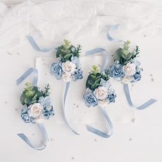 three boutonnieres with blue and white flowers on them