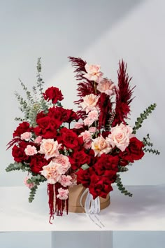 a vase filled with red and pink flowers sitting on top of a white countertop