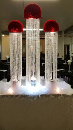 two tall vases with red flowers on top of a white table cloth covered in crystal beads