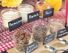 there are many different types of food in jars on the table with utensils