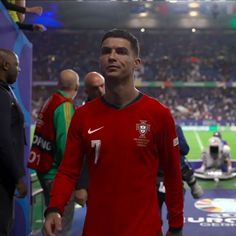 a soccer player is standing in the middle of a stadium with other players behind him