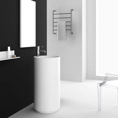 a white sink sitting next to a black wall in a bathroom under a mirror and towel dispenser