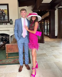 a man in a suit and tie standing next to a woman wearing a pink dress