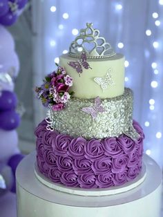 a three tiered cake with flowers and butterflies on it's top, sitting in front of purple balloons