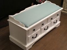 a white bench with drawers and a blue cushion