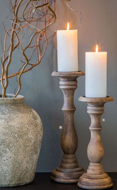 three candles are sitting on a table next to a vase