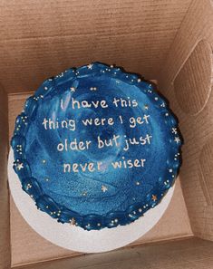 a blue cake in a cardboard box with writing on the side and stars around it