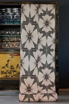 an old cabinet with a curtain that has been decorated in black and white designs on it