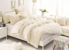 a white bed with fluffy blankets and pillows