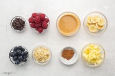 the ingredients in bowls are ready to be put into their respective dishes, including bananas, raspberries, chocolate chips, and peanut butter