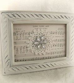 an old sheet music with a flower in the middle is framed on a white wall