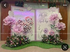 two large pink flowers on display in front of a sign that says happy women's day