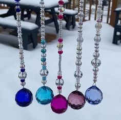 several different colored beads hanging from chains in the snow with benches in the back ground