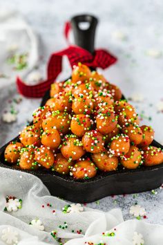 a black bowl filled with orange and green sprinkles on top of a table