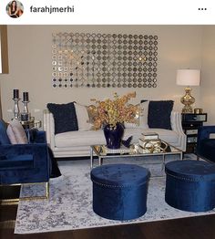 a living room filled with blue velvet furniture and gold accents on the wall above it