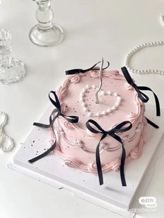 a pink cake with pearls and a heart on it