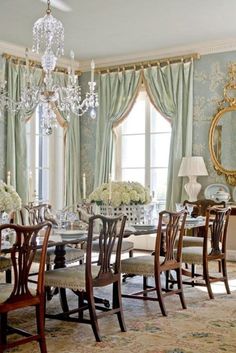 a formal dining room with chandelier, chairs and table in front of windows