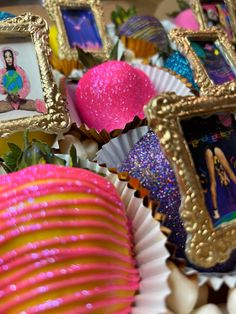 there are many pictures on the table with pink and yellow decorations around them, including framed photos