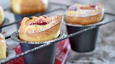 several pastries are sitting on trays with powdered sugar and jelly in them