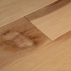 a close up of a wooden floor with a knife on it's end and a piece of wood in the background