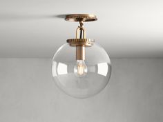 a clear glass globe light hanging from a ceiling fixture in a room with white walls