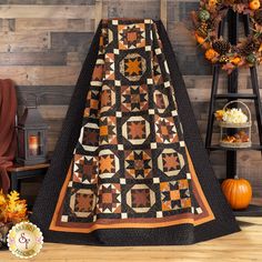 a quilted blanket sitting on top of a wooden floor next to a pumpkin wreath