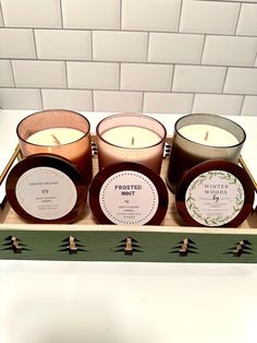 three candles sitting on top of a wooden tray