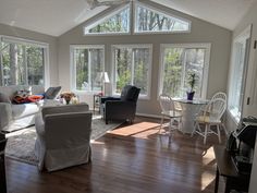 a living room filled with furniture and windows covered in white coverings on top of hard wood flooring