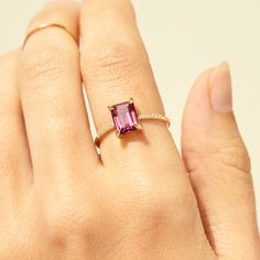 a woman's hand wearing a ring with a pink tourmaline stone on it