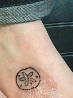 a small sand dollar tattoo on the ankle