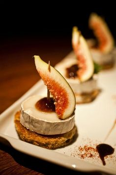 three desserts on a white plate with figs and sauce