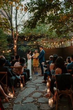 a couple getting married at their backyard wedding in the evening with candles lit on the ground