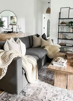 a living room filled with lots of furniture next to a wooden coffee table in front of a mirror