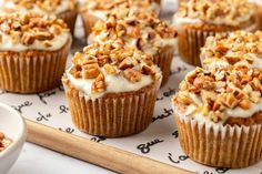 cupcakes with white frosting and chopped walnuts are on a baking sheet