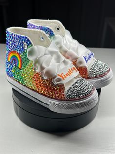 Custom Kids Bling Rainbow Converses. Any theme can be customized and made. Perfect for special occasions, dress down days, or just because! Be bold and show who you are with a customized pair, & dare to be different! All crocs are made to order. Please be as detailed as possible when describing what you would like (shoe size, shoe color, stone color(s), rhinestones, pearls, rhinestone & pearl mix, patches, theme, ect). If you're unsure of what you would like, please feel free to reach out for more ideas & I'll be happy to assist. Names can be added to shoe with vinyl. Ribbon shoe strings can be customized with a name.  Processing times are from 2 - 4 weeks. *Due to the nature of items being made to order, refunds and returns are not accepted* If you need to make a change after placing your Bling Out Converse, Bedazzled Shoes Diy Rhinestone Converse, Purple Bling Converse, Rainbow Custom Sneakers For Streetwear, Rainbow Converse, Bling Converse Toddler, Ribbon Shoes, Dress Down Day, Bedazzled Shoes