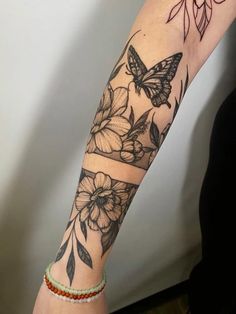 a woman's arm with a butterfly and flowers tattoo on the left side of her arm