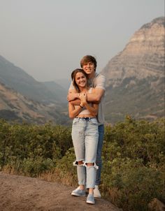 a man and woman hugging on top of a mountain