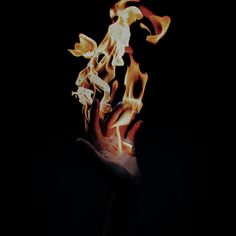 a hand holding out flames in the dark