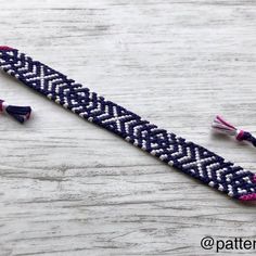 a blue and white bracelet with tassels sitting on top of a wooden table