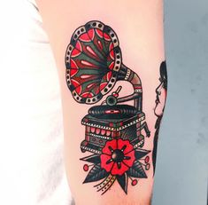 a man with a tattoo on his arm has a red flower and a record player