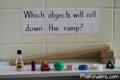 a sign that reads which objects will roll down the ramp? with other toys on top